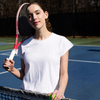 Woman in an Ivory CourtLife Pique Tee holding a red tennis racquet over her shoulder by the net on a tennis court